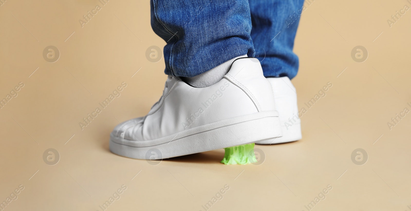 Photo of Person stepping into chewing gum on light brown background, closeup