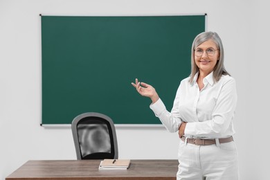 Photo of Portrait of professor near blackboard in classroom, space for text