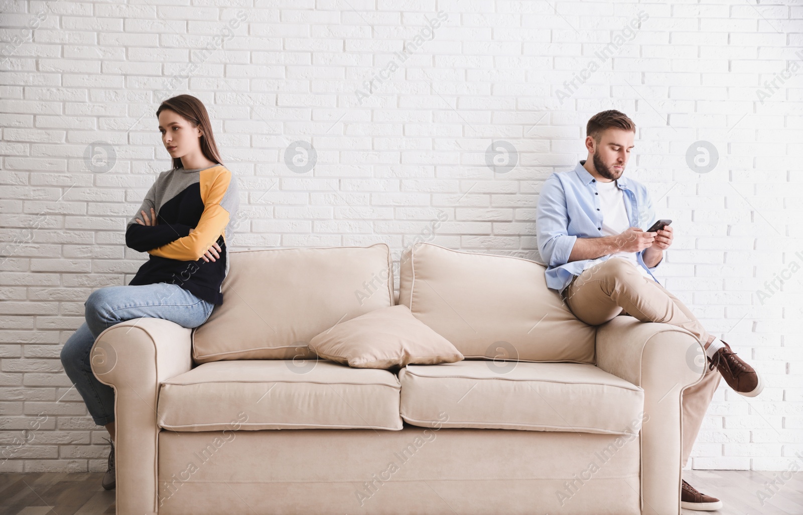 Photo of Young man preferring smartphone over his girlfriend at home. Relationship problems