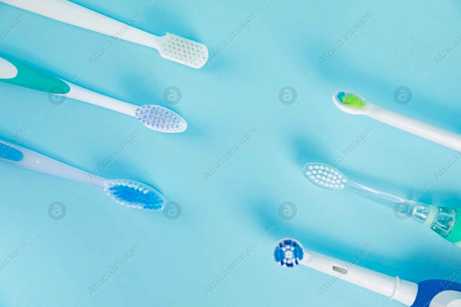 Photo of Electric toothbrushes on light blue background, flat lay