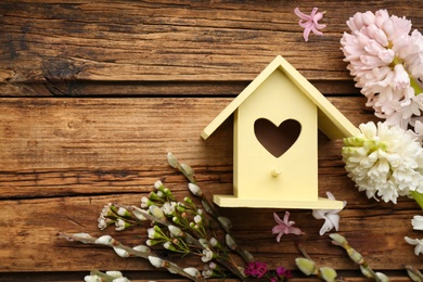 Photo of Flat lay composition with bird house and flowers on wooden background. Space for text