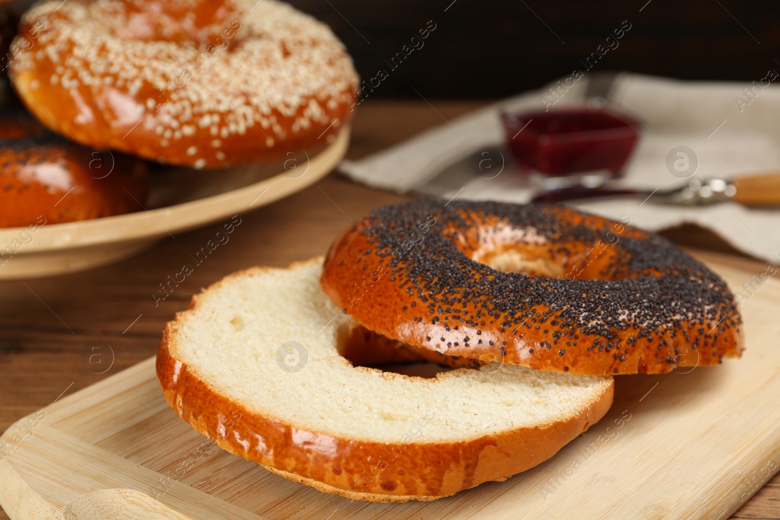 Photo of Delicious fresh halved bagels on wooden board, closeup