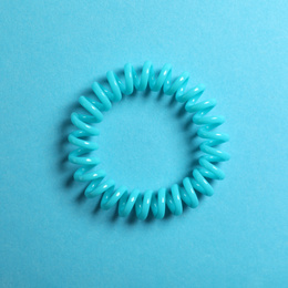 Stylish spiral rubber band on blue background, top view