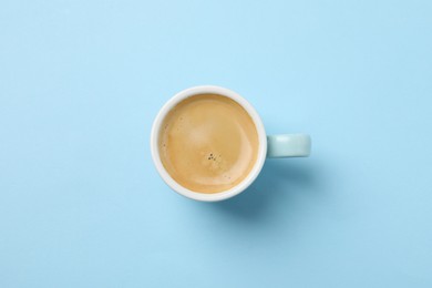 Photo of Aromatic coffee in cup on light blue background, top view