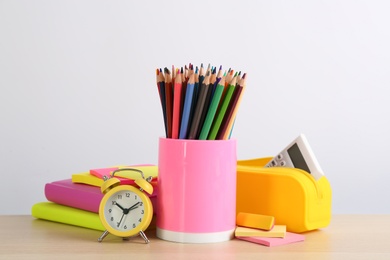 Different school stationery and alarm clock on table against white background. Back to school