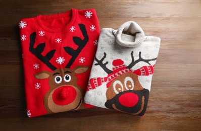 Folded warm Christmas sweaters on wooden table, flat lay