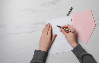 Woman writing letter at marble table, top view