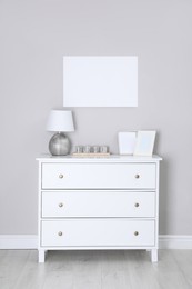 Photo of Blank canvas on wall over chest of drawers with decor indoors. Space for design