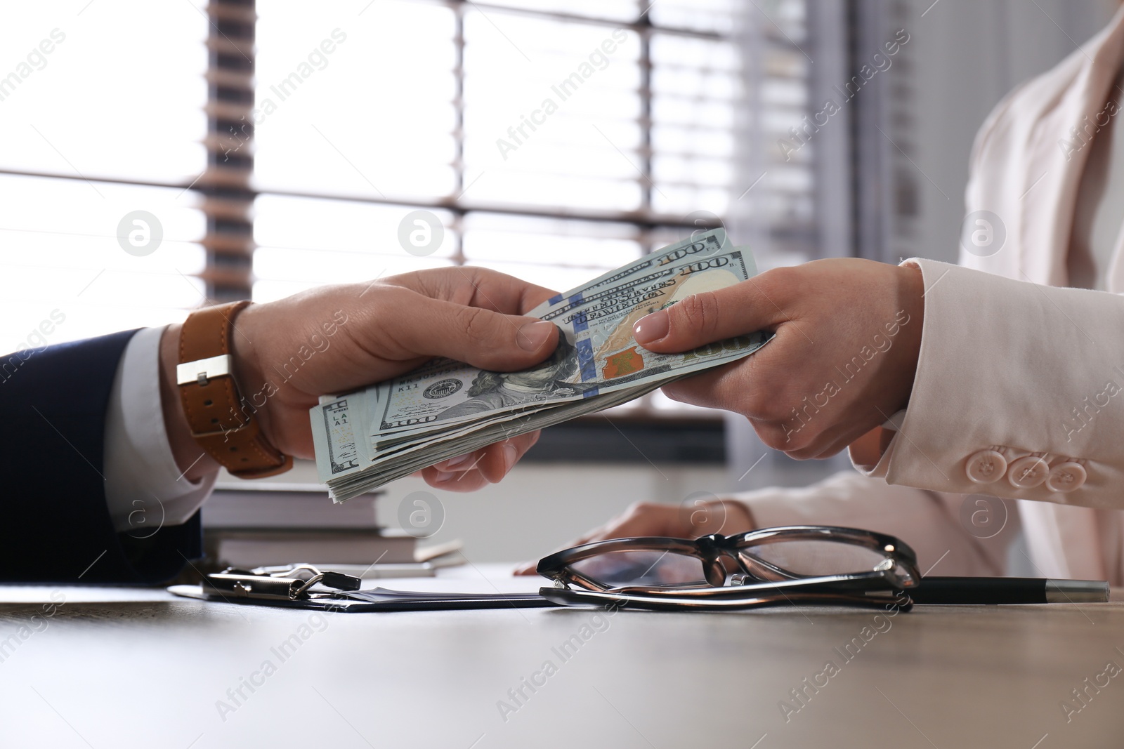 Photo of Man giving bribe to woman at table in office, closeup