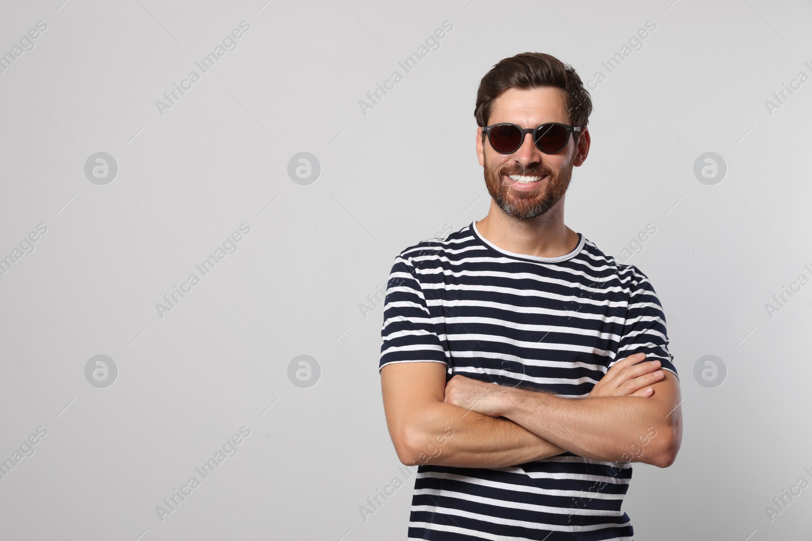 Photo of Portrait of smiling bearded man with stylish sunglasses on light background. Space for text