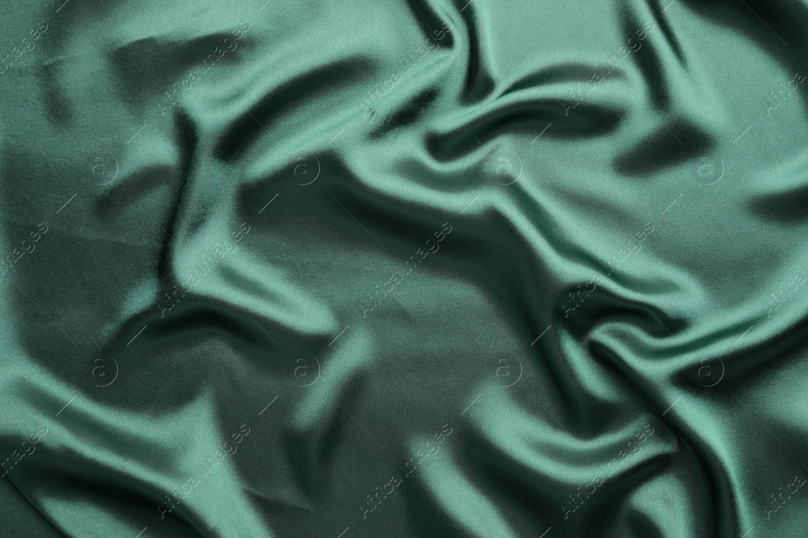 Photo of Crumpled green silk fabric as background, top view