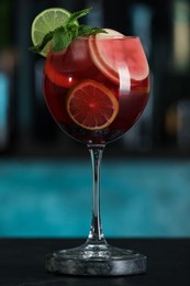Photo of Delicious sangria cocktail on black table in bar