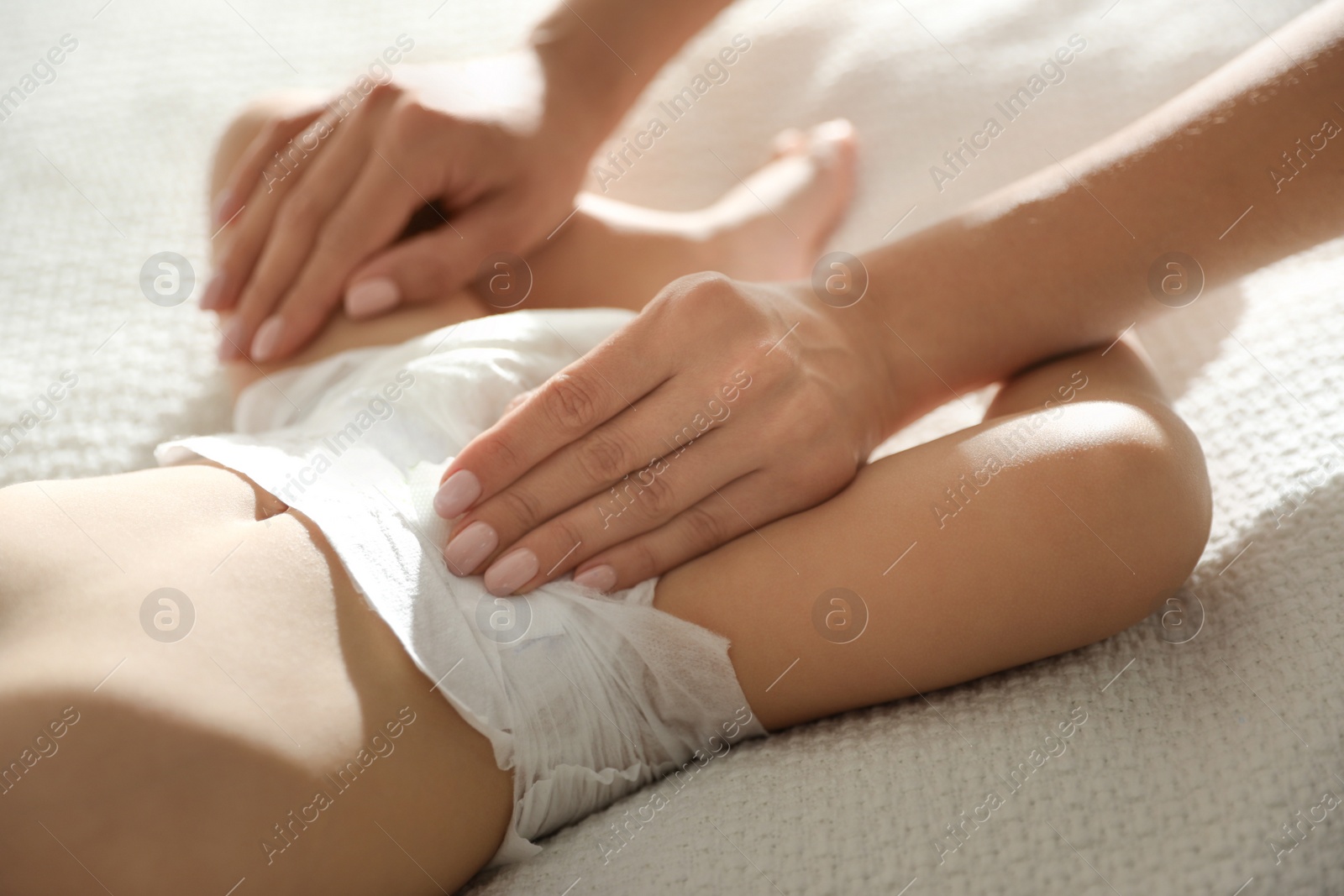 Photo of Mother changing baby's diaper on bed at home, closeup