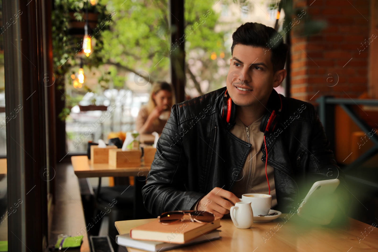 Photo of Man with headphones and smartphone at table in cafe