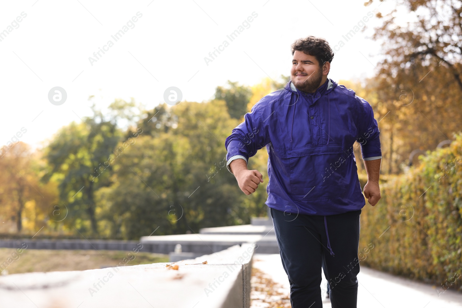 Photo of Young overweight man running in park. Fitness lifestyle