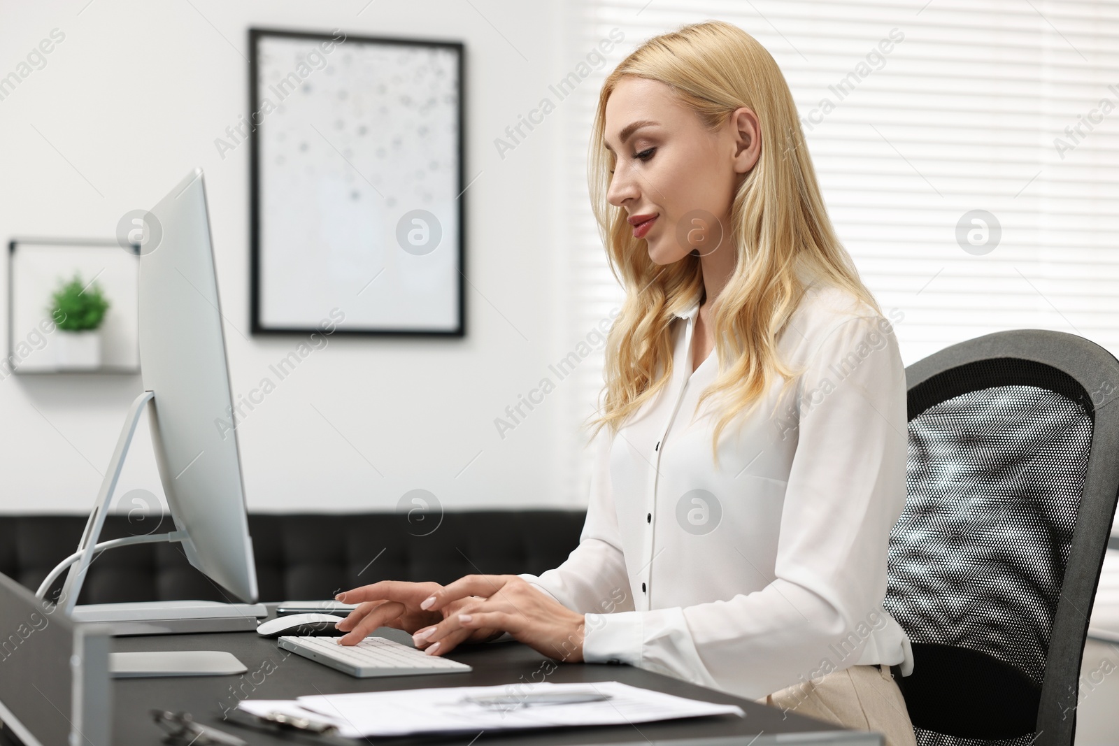 Photo of Secretary working on computer at table in office