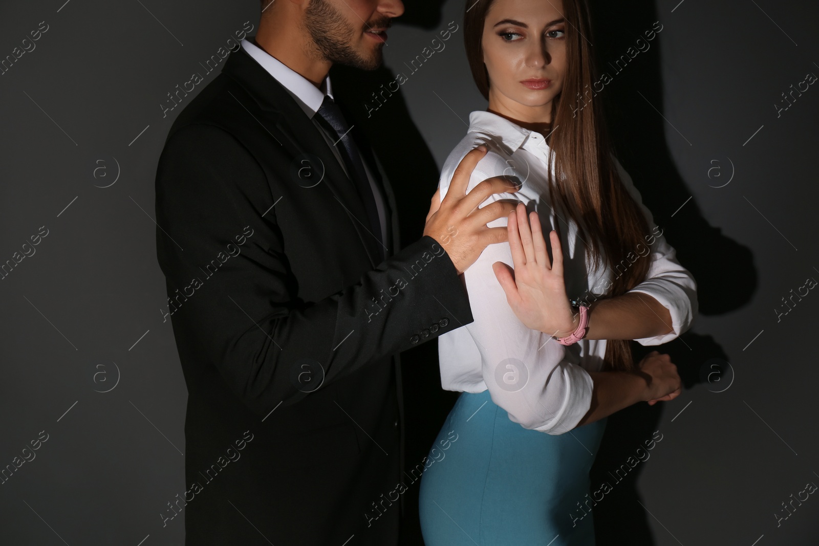 Photo of Boss molesting his female secretary on dark background. Sexual harassment at work