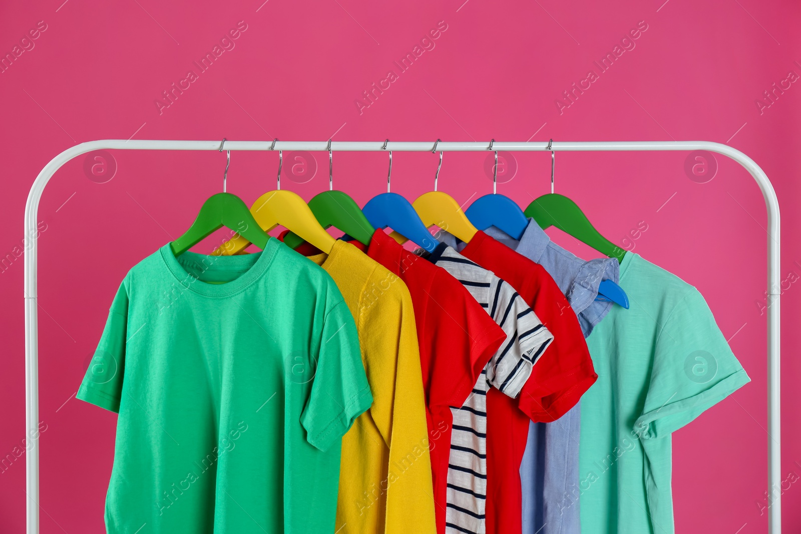 Photo of Rack with stylish children clothes on pink background