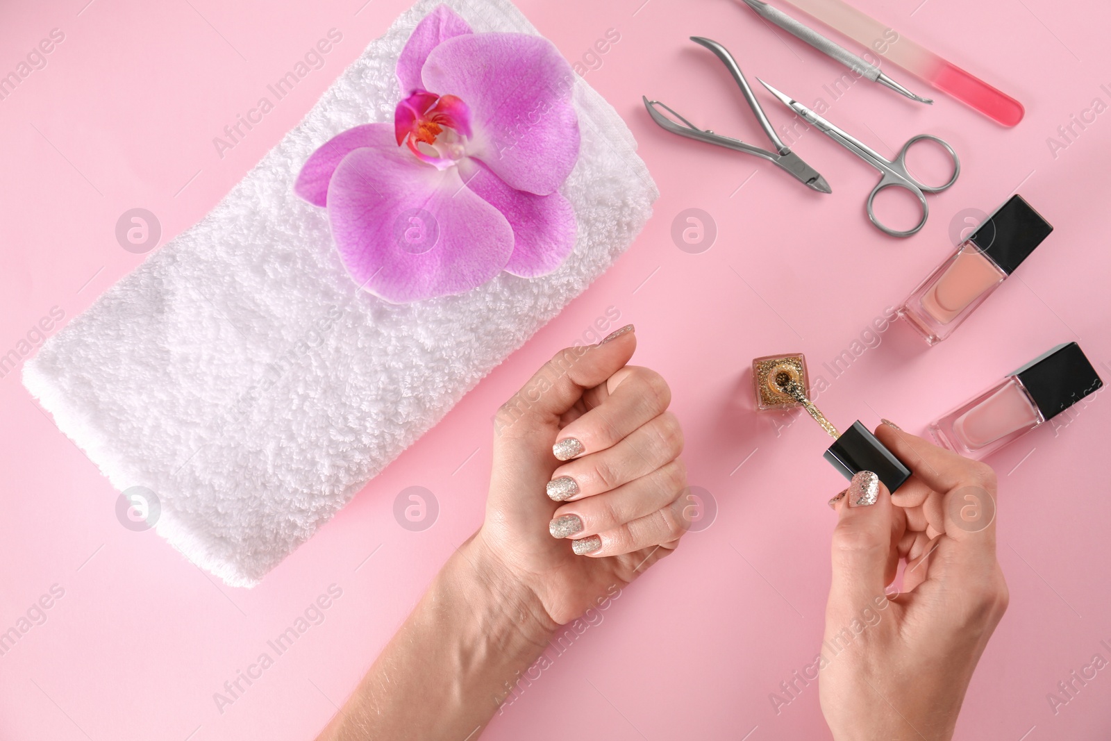 Photo of Woman applying nail polish on color background, top view