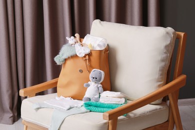 Photo of Mother's bag with baby's stuff on armchair indoors