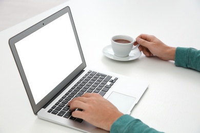 Photo of Young man working with modern laptop at table, closeup. Mockup for design