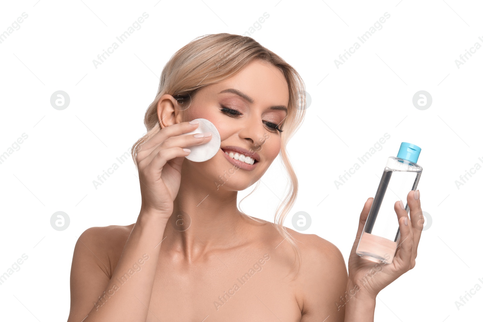 Photo of Smiling woman removing makeup with cotton pad and holding bottle on white background