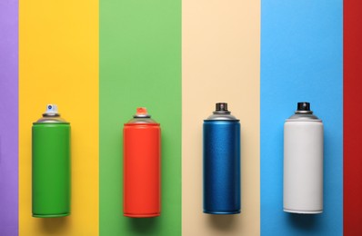 Photo of Cans of different spray paints on color background, flat lay with space for text. Graffiti supplies