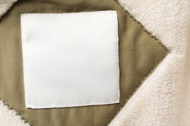 Photo of Clothing label on beautiful soft garment, top view