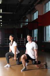 Photo of Couple working out with dumbbells in gym
