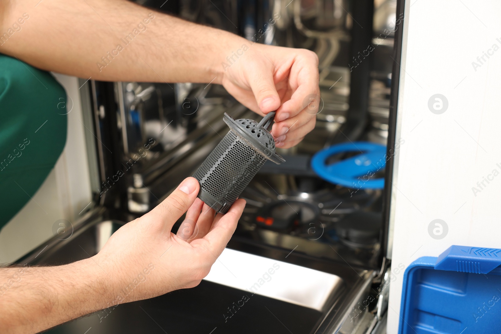 Photo of Repairman holding drain filter near dishwasher, closeup