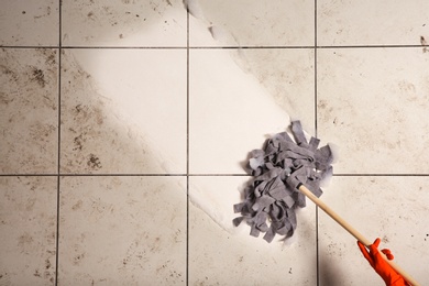 Professional cleaner washing dirty floor with mop, top view. Space for text