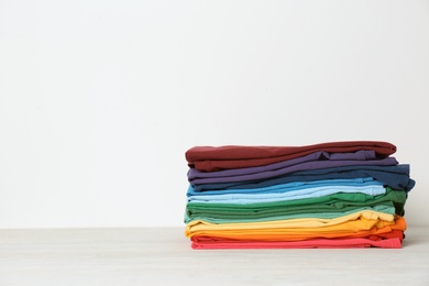 Stack of bright folded clothes on table against white background. Space for text