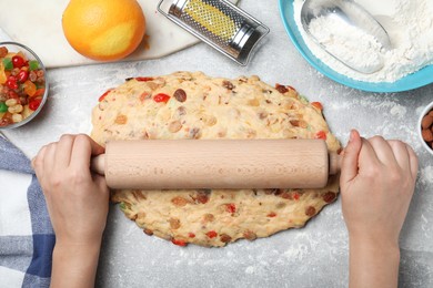 Photo of Woman rolling dough for Stollen at grey table, top view. Baking traditional German Christmas bread