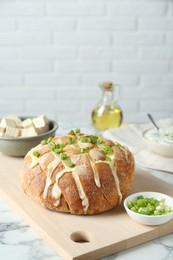 Freshly baked bread with tofu cheese and green onion on white marble table