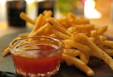 Delicious hot french fries with red sauce served on table, closeup