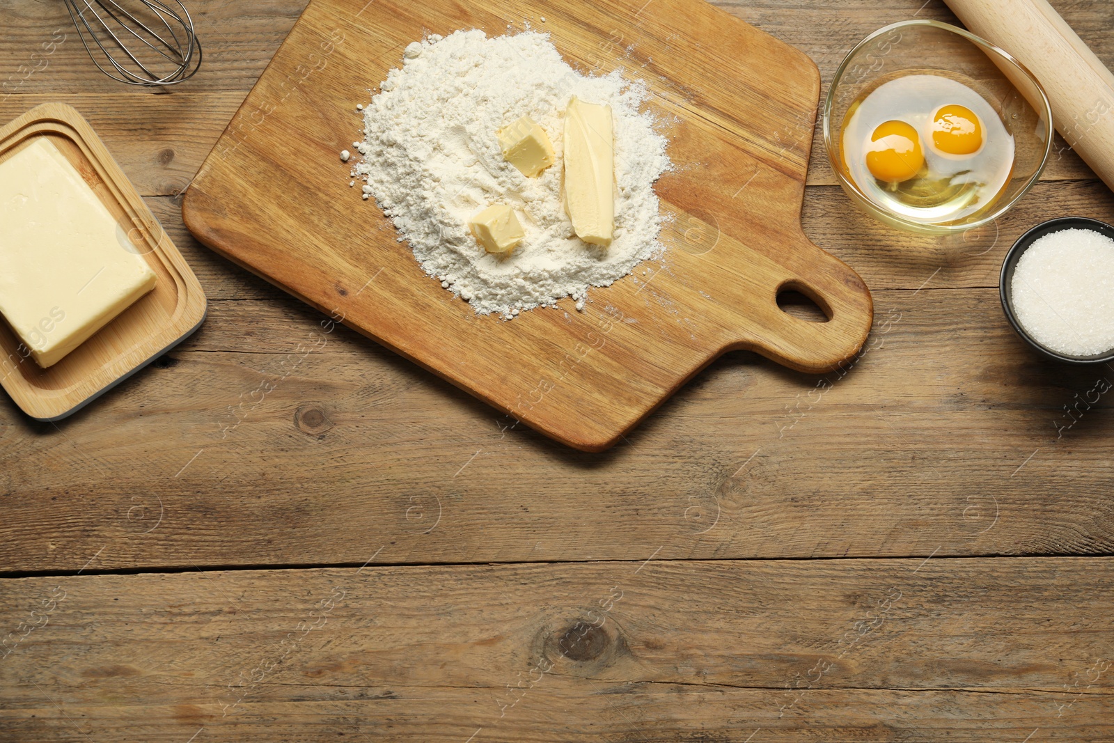 Photo of Board with fresh butter and flour on wooden table, flat lay. Space for text