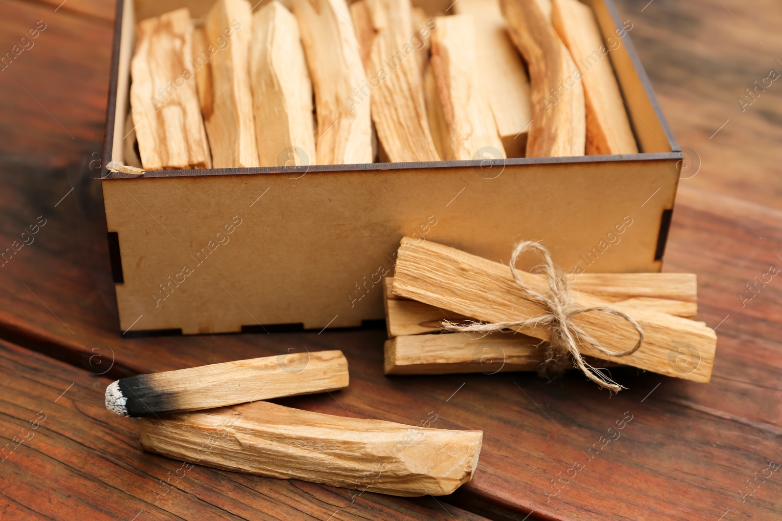 Photo of Many Palo Santo sticks and one smoldering on wooden table