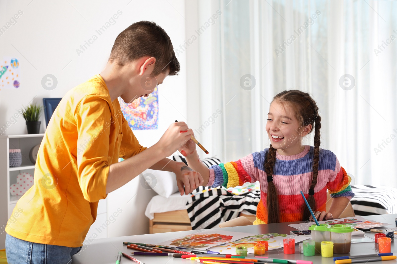 Photo of Little children having fun with paints at table indoors