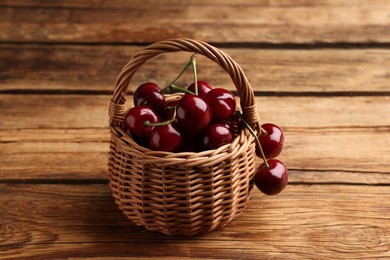Photo of Wicker basket of ripe sweet cherries on wooden table