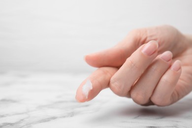 Photo of Woman applying petroleum jelly onto her finger at white table, closeup