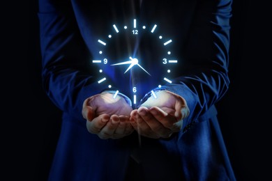 Image of Man holding virtual icon of clock on dark background, closeup. Time management