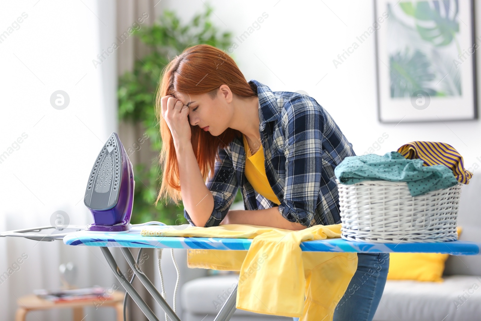 Photo of Tired housewife ironing clothes at home