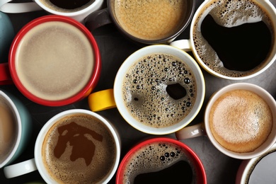 Many cups with tasty aromatic coffee on table, flat lay