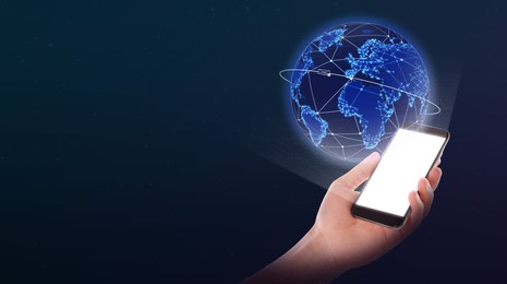 Image of Global network. Man holding smartphone with digital image of Earth on dark blue background. Banner design with space for text