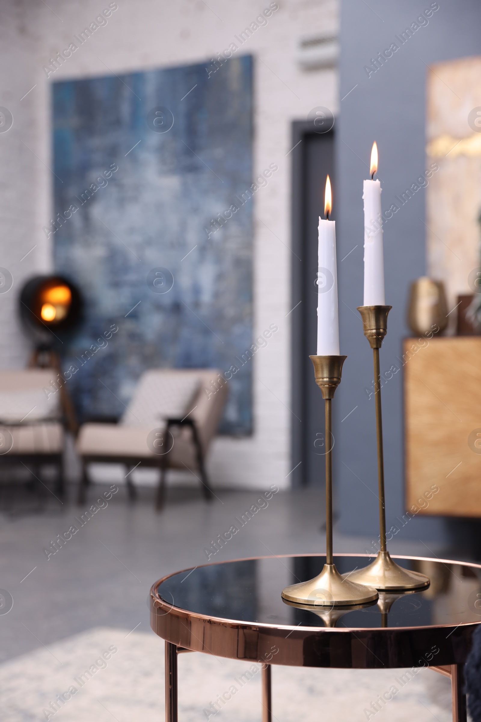 Photo of Pair of beautiful candlesticks on glass table in room, space for text