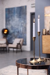 Pair of beautiful candlesticks on glass table in room, space for text