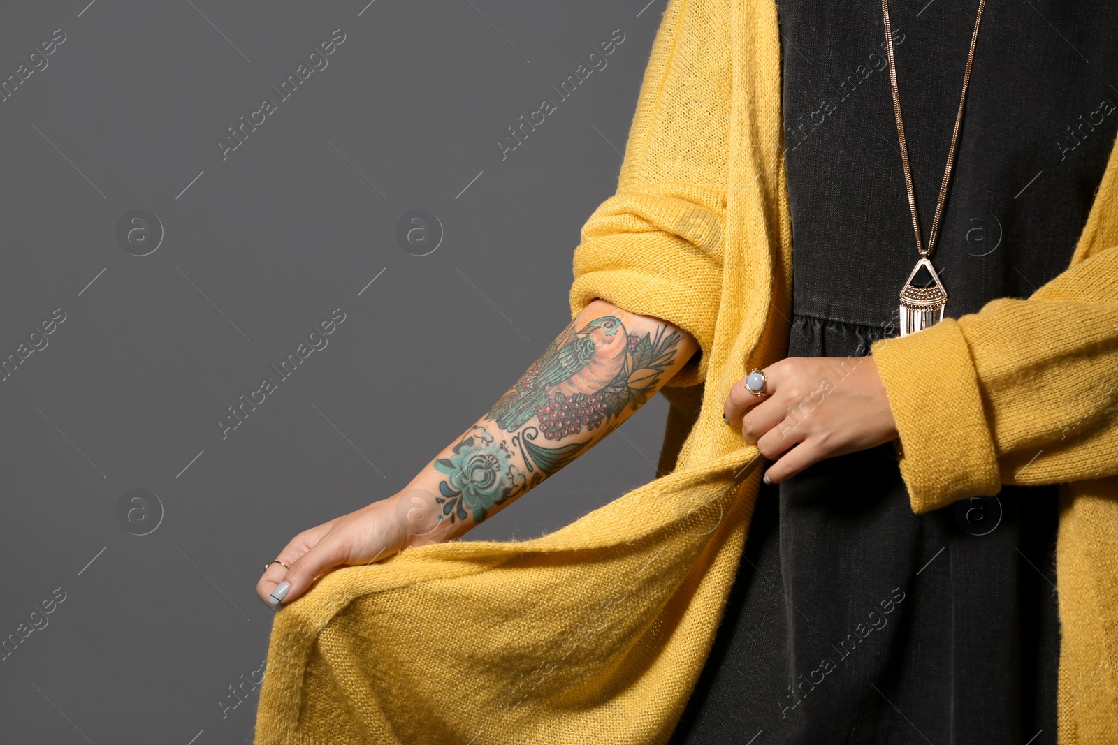 Photo of Trendy young woman with tattoo on grey background, closeup. Space for text