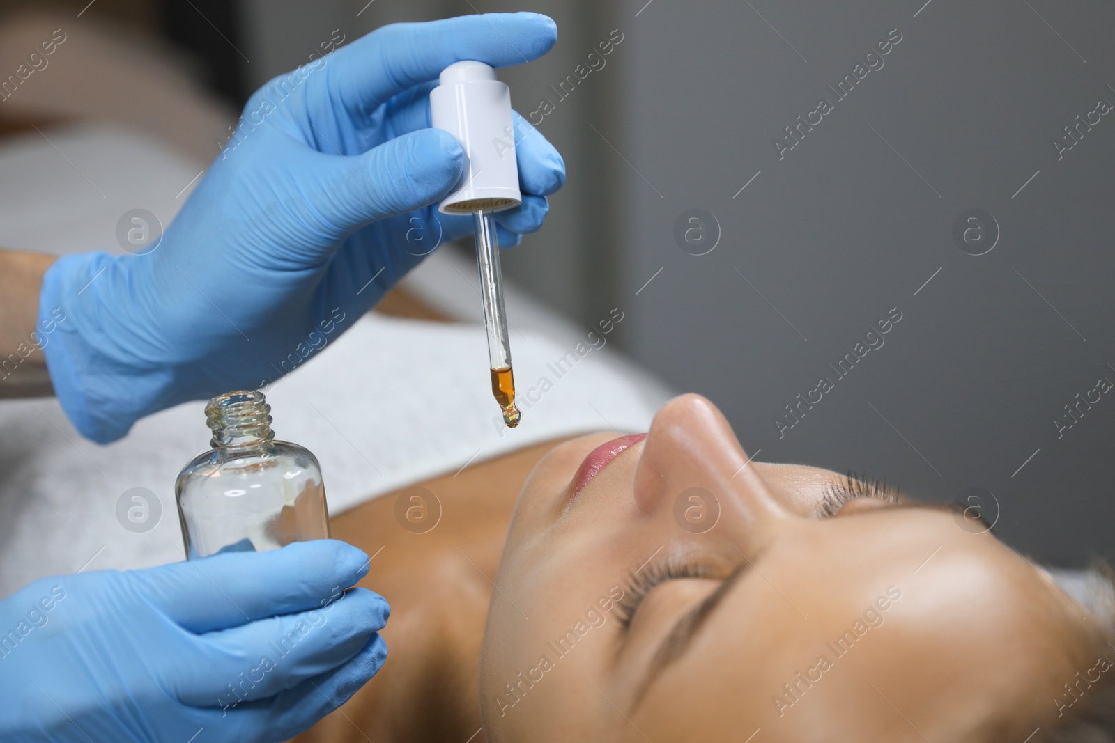 Photo of Cosmetologist applying serum on client's face in salon