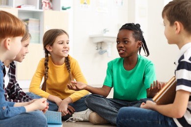 Photo of Cute children discussing in classroom at school