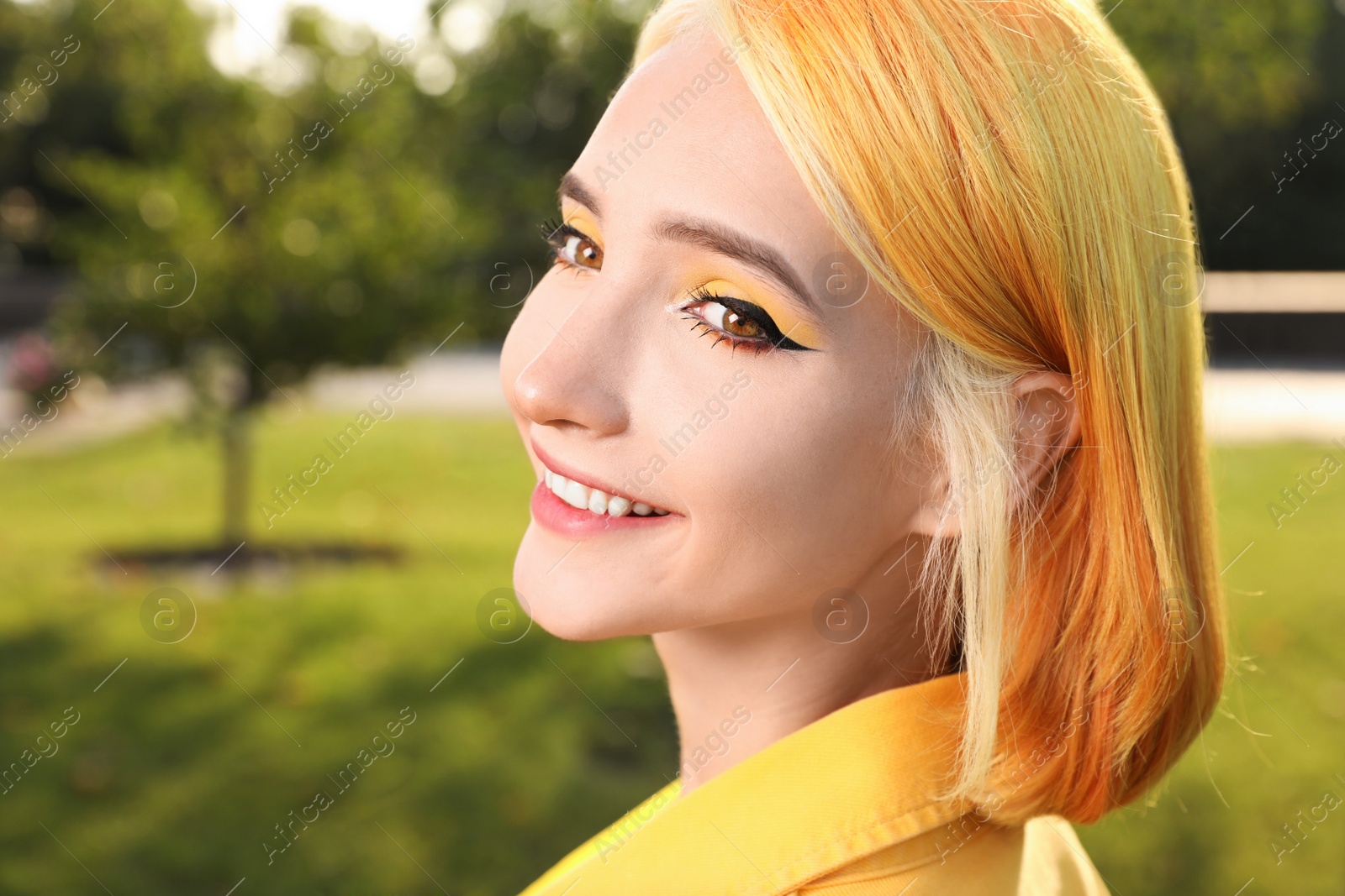 Photo of Beautiful young woman with bright dyed hair holding penny board in park